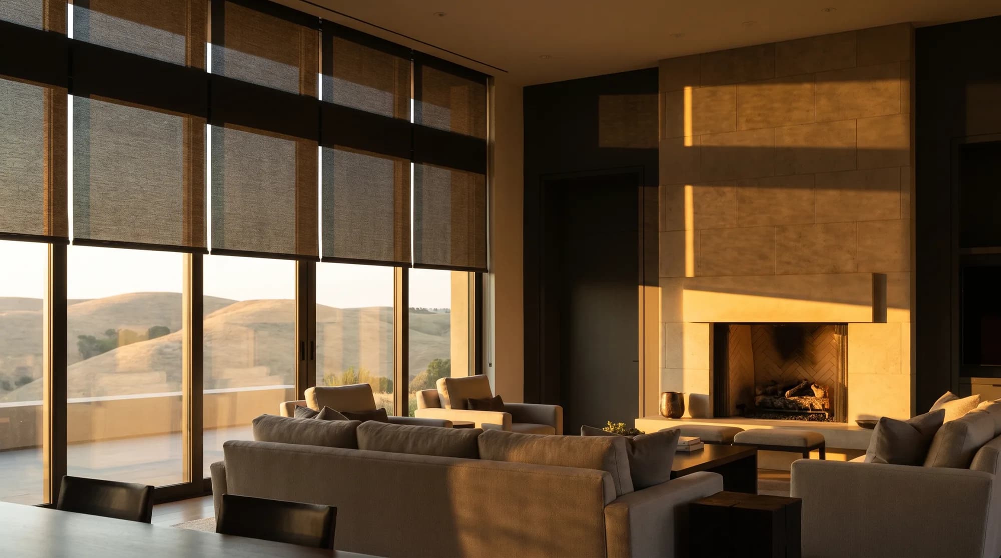Great room with motorized shades lowered in unison at golden hour