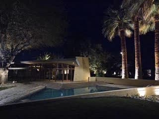 Pool with uplit palms and the house beyond