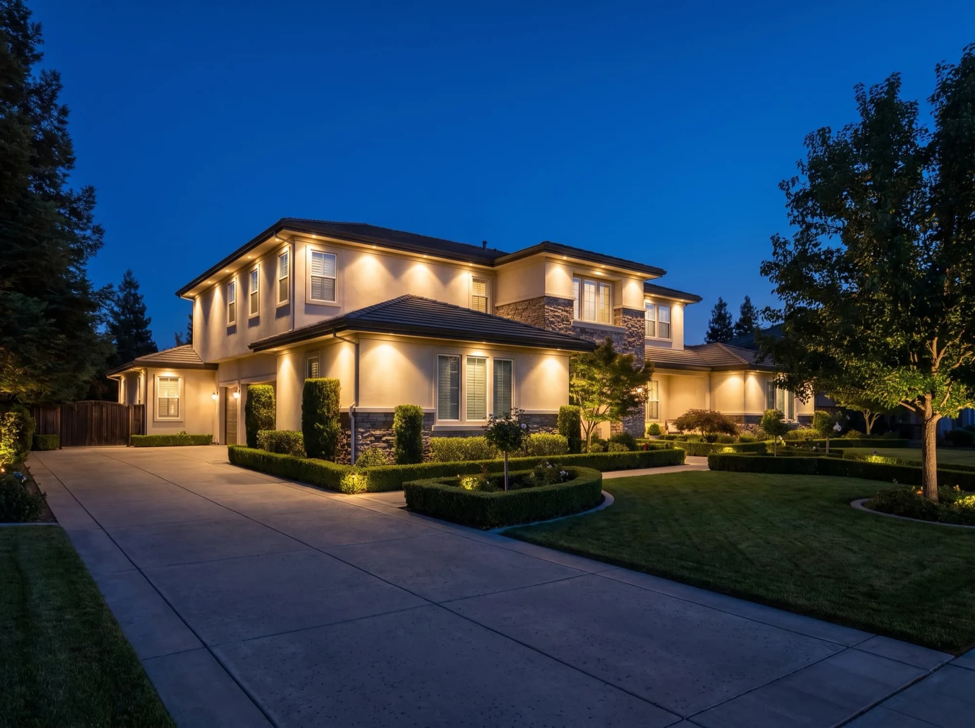 Custom home washed in warm architectural lighting at dusk