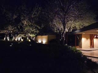 Front approach with uplit trees and glowing porch