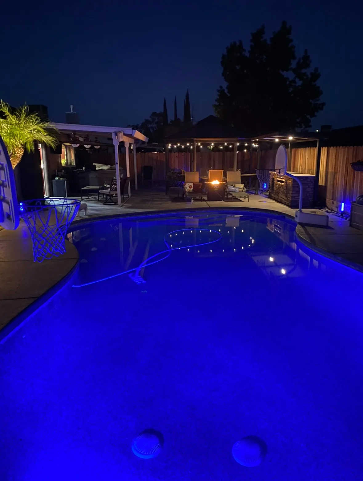 Backyard pool glowing blue under a covered patio