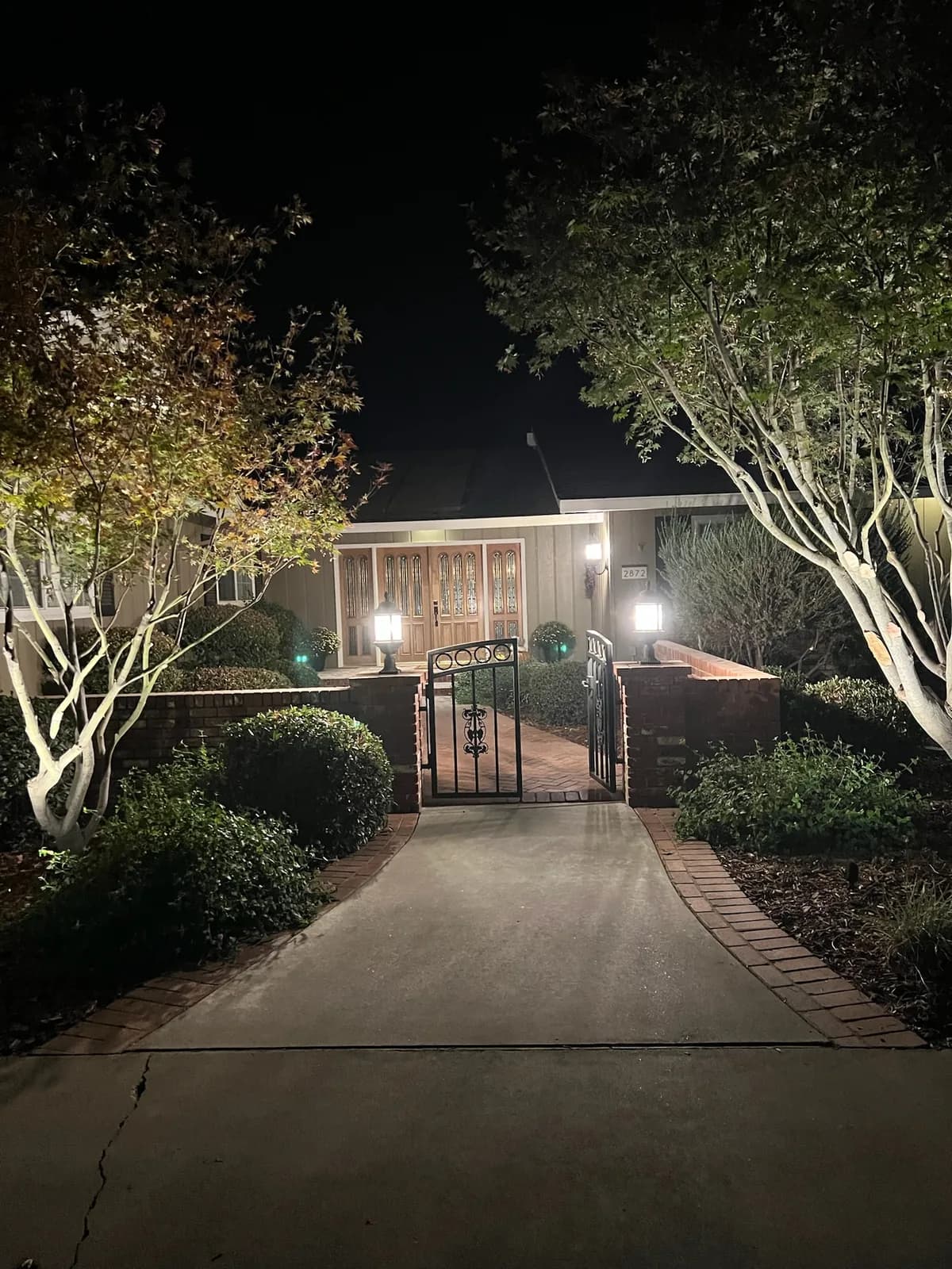 Driveway entry with uplit trees and gate