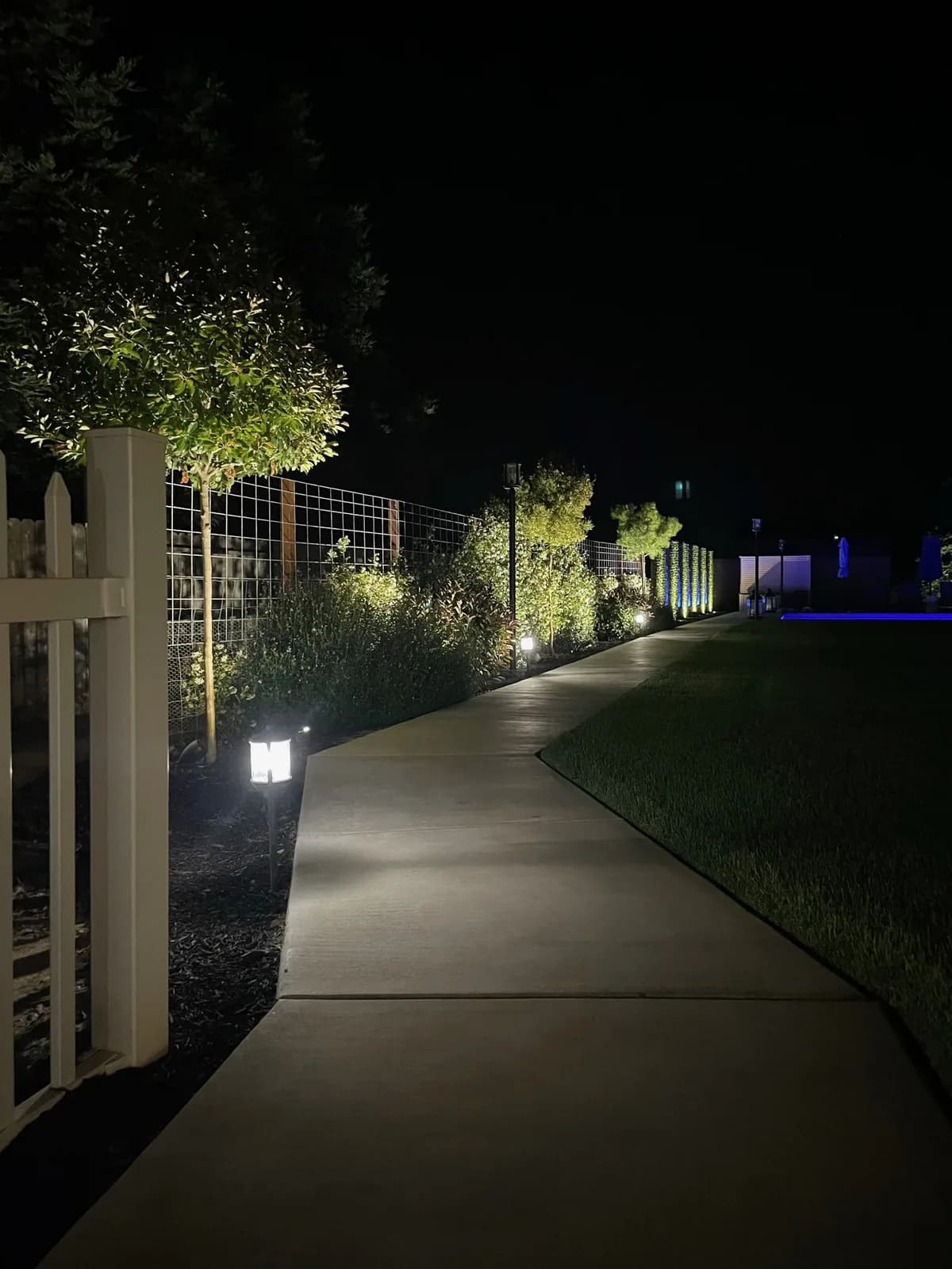 Garden gate and lit path along a lawn