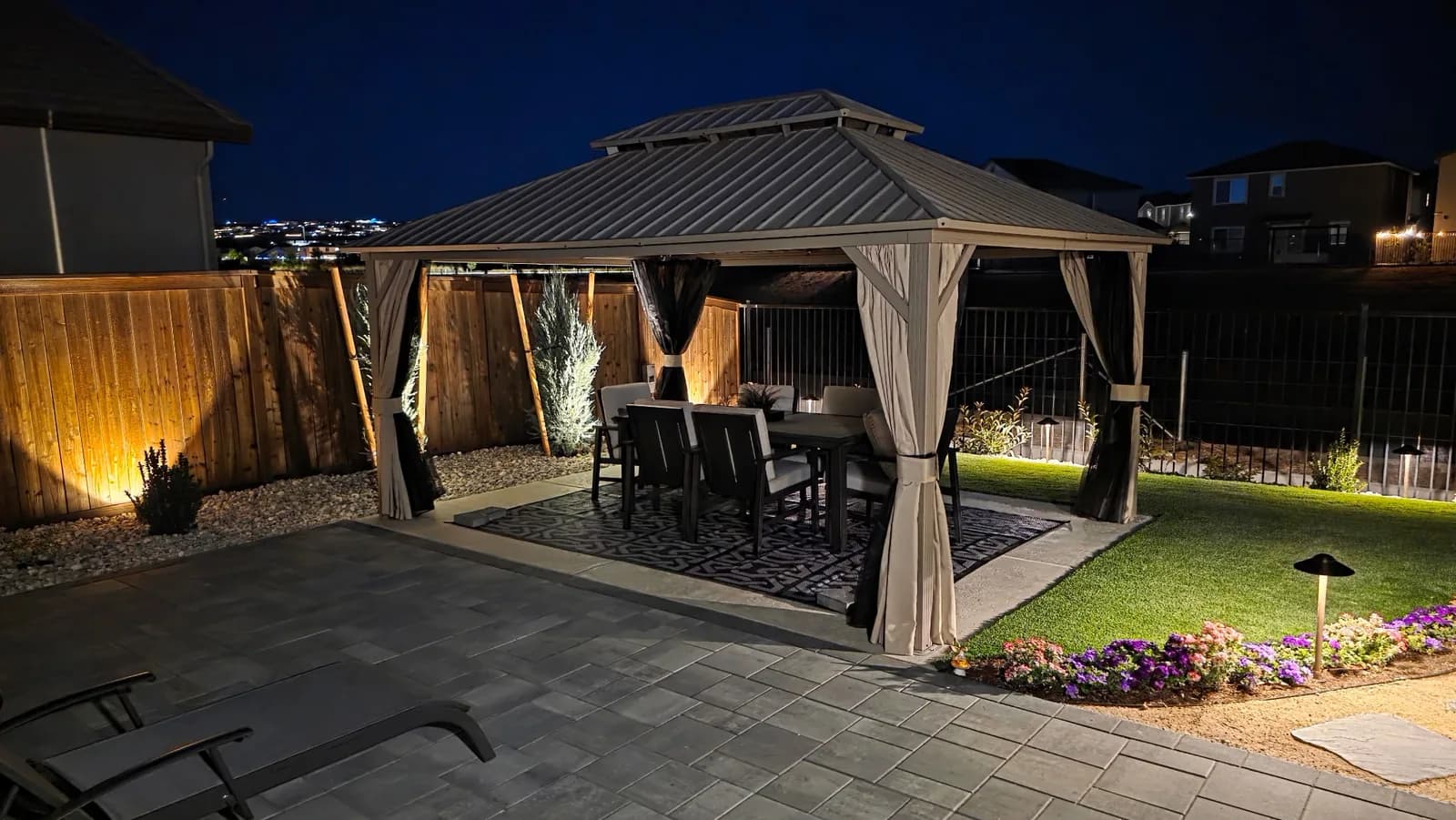 Backyard gazebo and paver patio lit at dusk