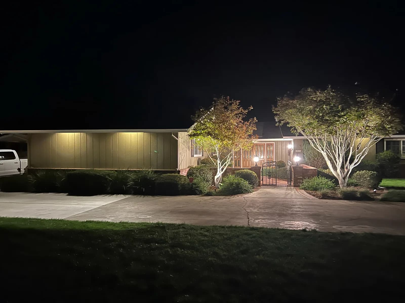 Ranch home with uplit front trees