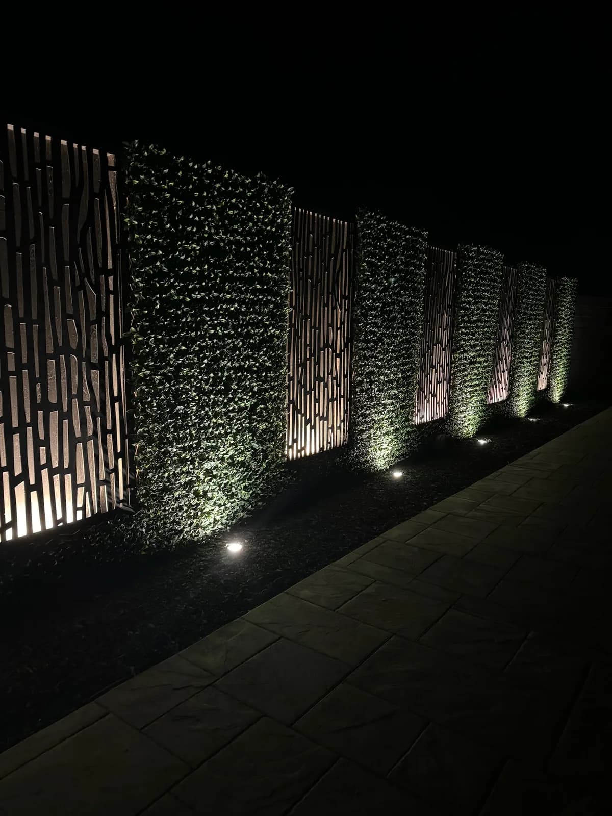 Laser cut screens set into a lit hedge